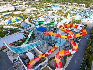 A water park with multiple slides and pools, surrounded by buildings and greenery.