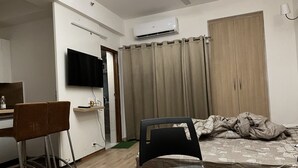 Ein gemütliches Schlafzimmer mit einem Bett, einem Schreibtisch mit Stuhl, einem Fernseher und einer Klimaanlage.