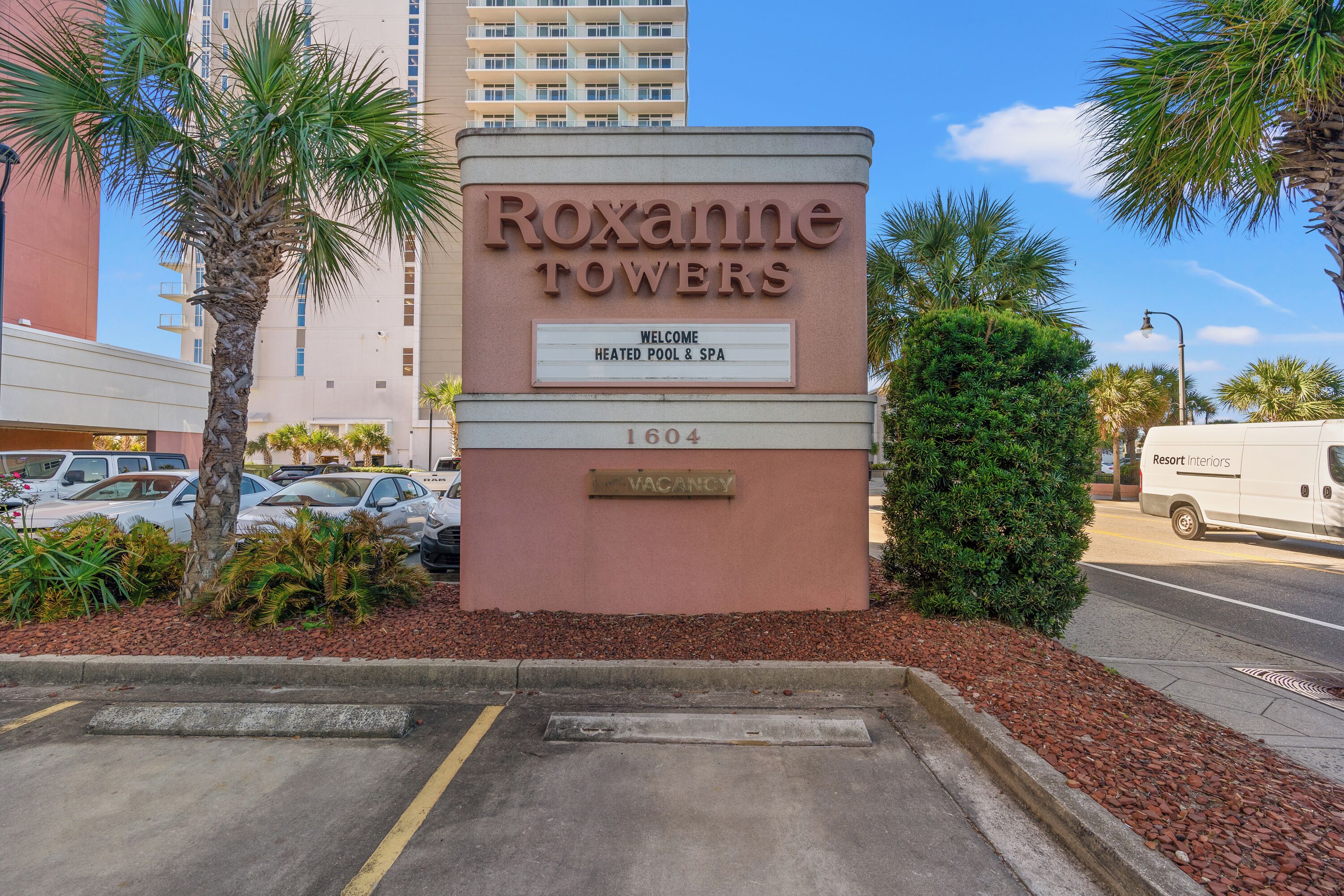 A sign for Roxanne Towers with a welcome message for a heated pool and spa.