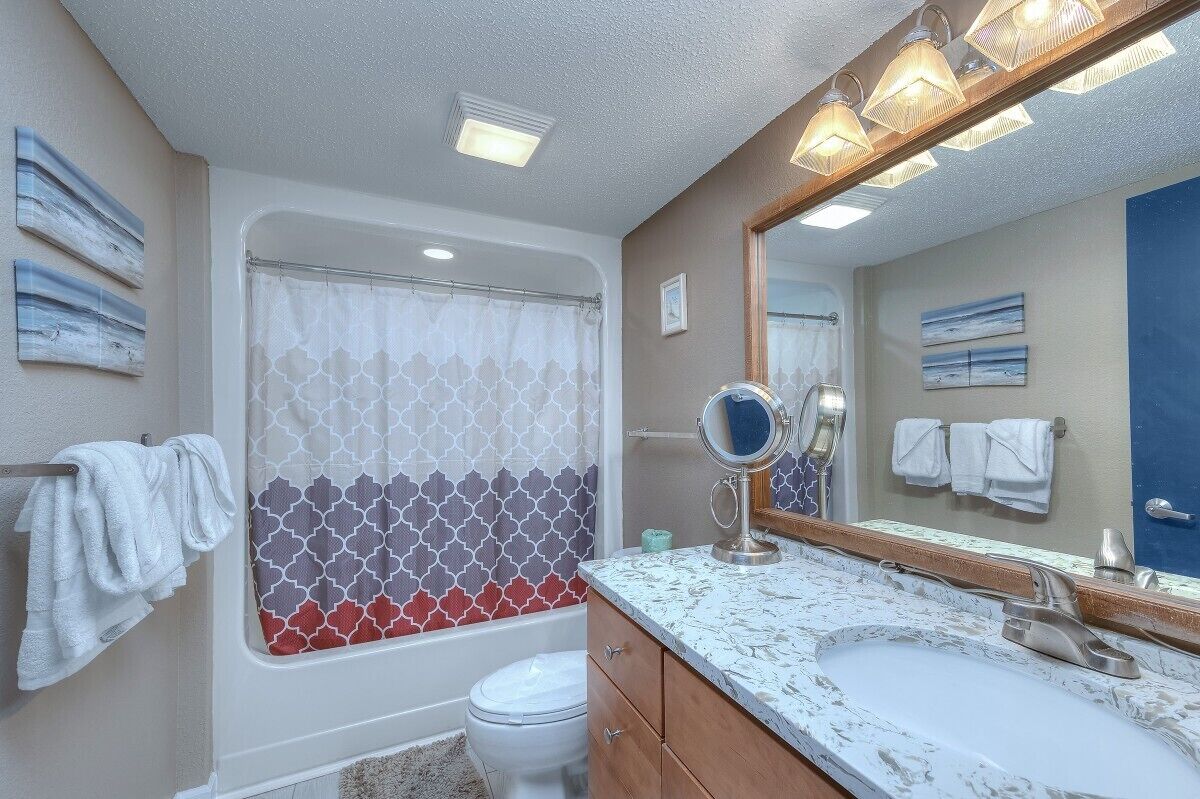 Een badkamer met douche, toilet, wastafel en een grote spiegel.