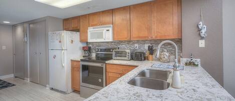 A modern kitchen with wooden cabinets, stainless steel appliances, and a marble countertop.