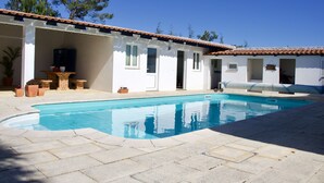 A swimming pool with a tiled deck, a covered patio area with seating, and a white building with a tiled roof. - Villa with fabulous views, pool, pool table, table tennis table, 15mins to beach (Amoreira, Obidos)