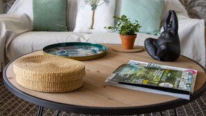 A round wooden table with a woven stool, a magazine, and a potted plant. - Villa de Vacance 6 Personnes (Orpierre)