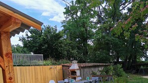 An outdoor patio with a wooden pergola, a barbecue grill, and a table with chairs.