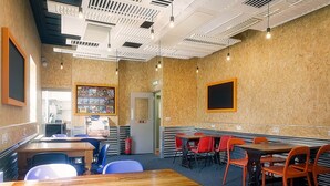 Un restaurante con mesas y sillas de madera, una barra con un menú y un extintor.