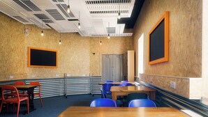 Une salle de conférence avec une table en bois, des chaises bleues, un tableau noir et une porte.