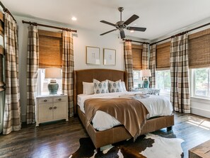 Une chambre avec un grand lit, un ventilateur de plafond et un tapis en peau de vache.