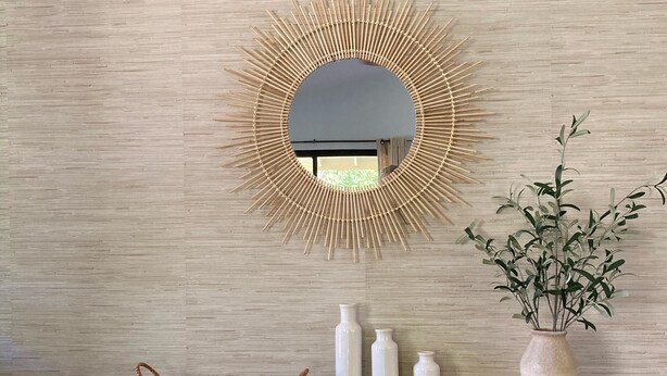 Un bureau en bois, agrémenté d’un panier tressé, de trois vases blancs et d’une plante en pot, le tout placé devant un mur à texture.