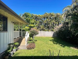 A house with a covered porch, a well-maintained lawn, and a wooden fence.