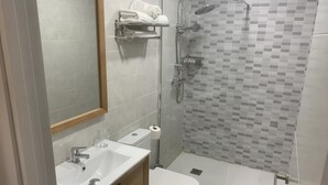 Casa de banho moderna com lavatório, sanita e chuveiro.