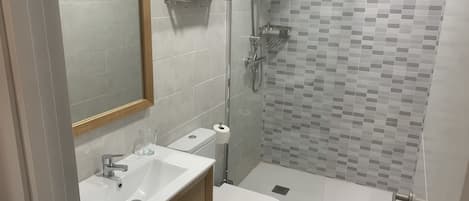 A modern bathroom with a sink, toilet, and shower.