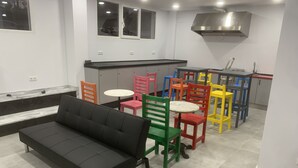 Cozinha moderna com sofá preto, cadeiras coloridas e uma mesa de jantar.
