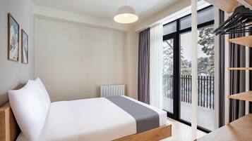 A modern bedroom with a bed, a radiator, a window with curtains, and a view of the outside.
