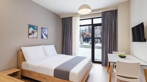 Una habitación de hotel moderna con una cama, un escritorio y vistas al exterior.
