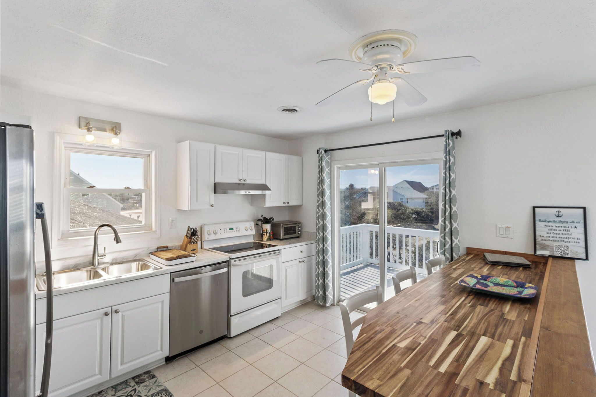 A modern kitchen with white cabinets, stainless steel appliances, and a wooden dining table.