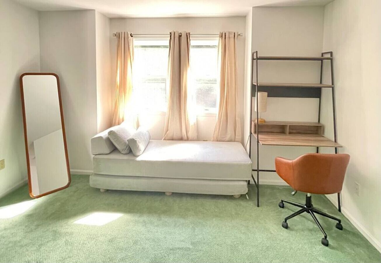 A room with a bunk bed, a desk, a chair, and a large mirror.