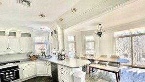Une cuisine moderne avec des meubles blancs, un îlot central et un coin repas comprenant une table et des chaises.