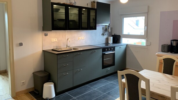 Een compacte keuken met een ingebouwde oven, een spoelbak en een raam dat voor natuurlijk licht zorgt.