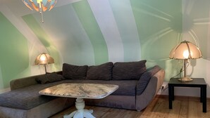Een gezellige woonkamer met een hoekbank, een bijzettafeltje en twee lampen.
