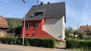 Een tweelaags huis met een rood-wit gevel, een pannendak en een schotelantenne.