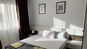 Una habitación de hotel con una cama, una mesita de noche y dos cuadros en la pared.