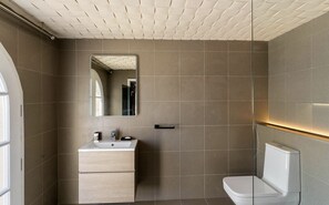 A modern bathroom with a large mirror, a sink, and a toilet.