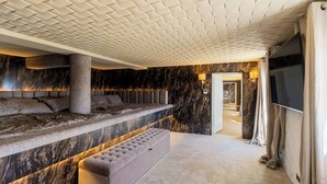 Una camera lussuosa con una parete in marmo, un letto grande, un’area salotto e una televisione.