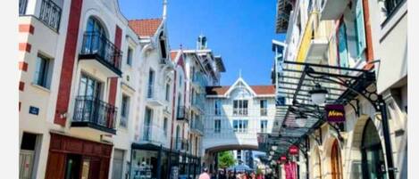 Una calle estrecha flanqueada por edificios de varios pisos, algunos con balcones y locales comerciales.