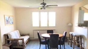A dining area with a round table and chairs, a sofa, and a ceiling fan.