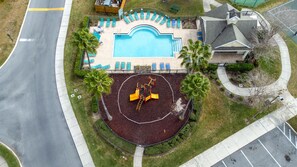 Relax by the resort's rectangular pool surrounded by lounge chairs and a children's play area with a slide and climbing structures.