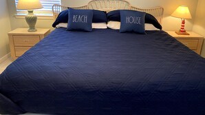 Un dormitorio con una cama grande, dos mesitas de noche, una ventana con persianas y un cuadro en la pared.