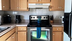 Una cocina con armarios de madera, un horno de acero inoxidable, una cafetera y un microondas.