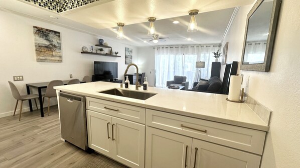 A modern kitchen with a central island, a built-in dishwasher, and a dining area with a table and chairs.