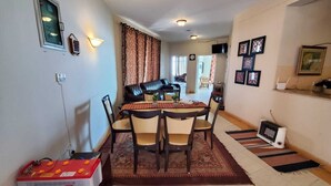 Un comedor con mesa y sillas, una ventana con cortinas y una lámpara fijada a la pared.