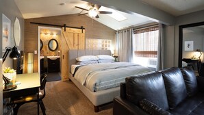 A modern bedroom with a large bed, a desk with a lamp, a leather couch, and a ceiling fan. - Cozy Swell House- Pet Friendly, Fenced Backyard: 2 King Beds (Page)