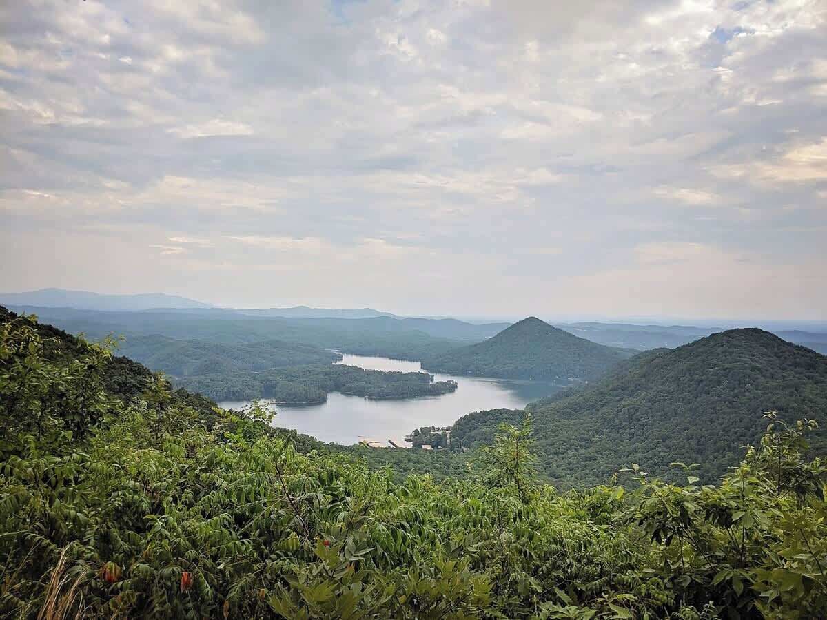 Een bergachtig landschap met een meer, omringd door dicht bos.