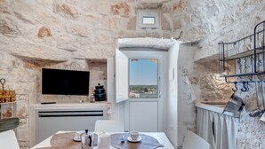 Un rincón comedor acogedor con una pared de piedra, un televisor de pantalla plana y vistas a través de un ventanal.
