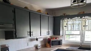 Uma cozinha com armários cinza, micro-ondas, pia e fogão.
