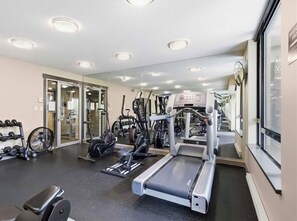 Academia com equipamentos de cardio, pesos e espelho.