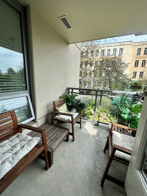 A balcony with a wooden bench, a chair, and a potted plant. - Perfectly Located Quality Downtown Home (Victoria)