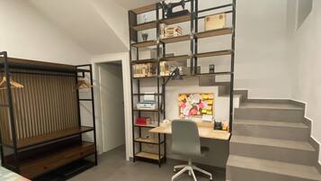 A bedroom with a bed, a desk with a chair, a bookshelf, and a staircase.