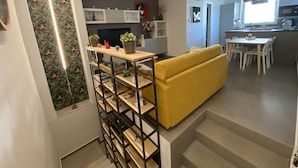A modern kitchen with a dining area, a yellow sofa, and a staircase with a wooden railing. - COMFORT HOUSE-Pompeii(archaeological excavations) (Pompei)