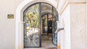 Une entrée en arc surmontée d’une porte en verre ornée de motifs métalliques décoratifs. Une enseigne au-dessus de la porte indique : « Villa Saint-Paul ».