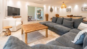 Un salon moderne avec un canapé gris, une table basse en bois et un téléviseur à écran plat.