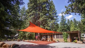 A cabin with a red canopy, surrounded by trees and a gravel driveway. - Upgraded Rustic Themed Retreat w/screened porch in Rocky Point. (Klamath Falls)