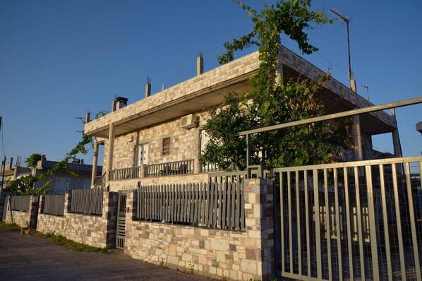 A stone building with a balcony, a gated entrance, and a clear sky.