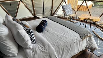 Un dormitorio tipo tienda de campaña con cama, almohadas y manta.
