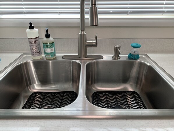 A stainless steel kitchen sink with two basins, a faucet, and a soap dispenser. - Mid Mod Home - 13 Min to Autzen - 6 Min to Airport (Eugene)