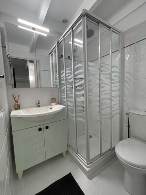 Une salle de bain moderne avec une douche à parois de verre, un lavabo blanc et des toilettes.