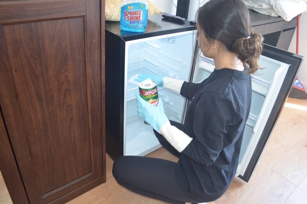 Una persona limpiando un refrigerador con una lata de peróxido de hidrógeno al 20%.